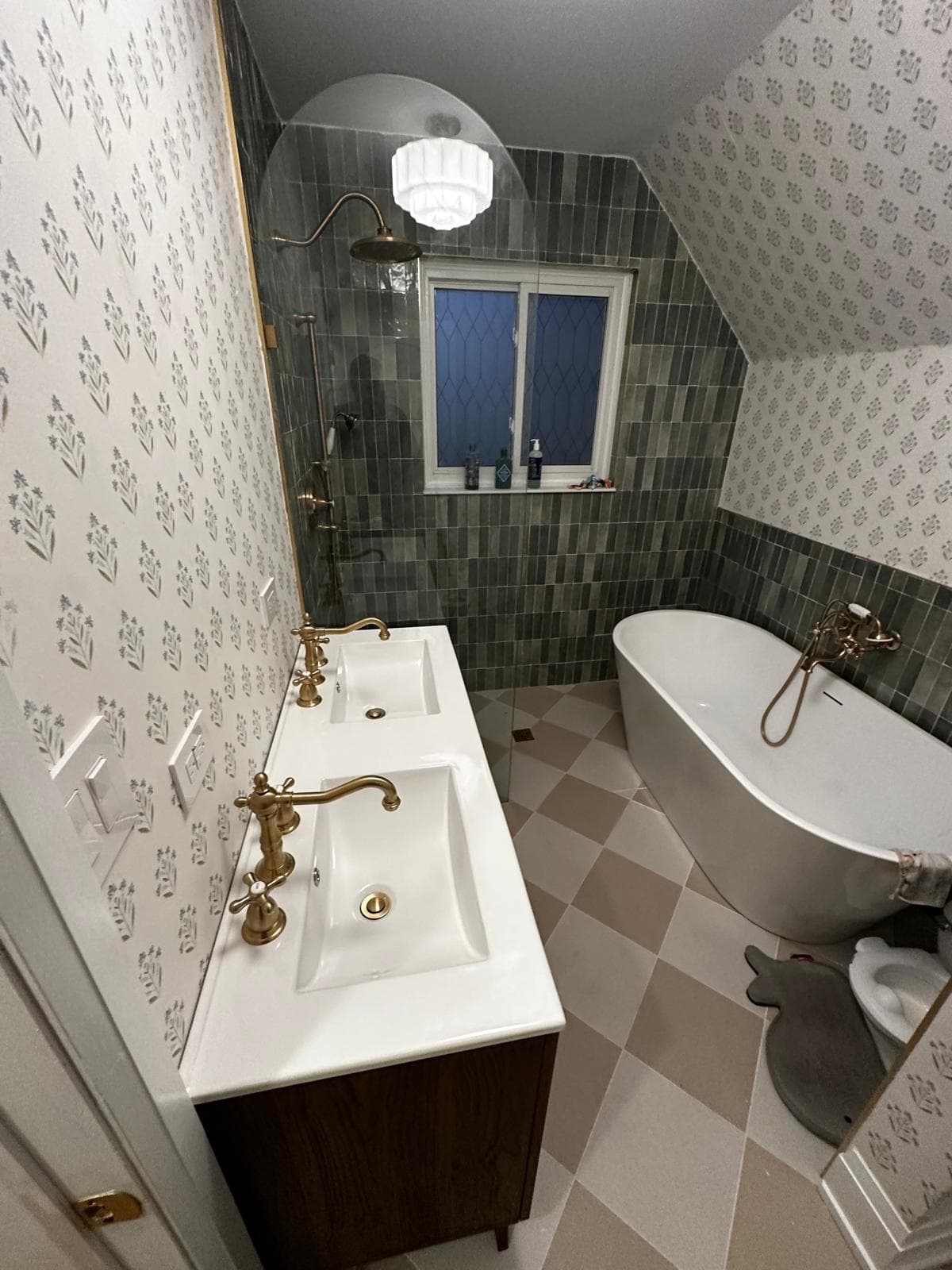 Bathroom with green vertical tile, brass fixtures, freestanding tub, and patterned wallpaper