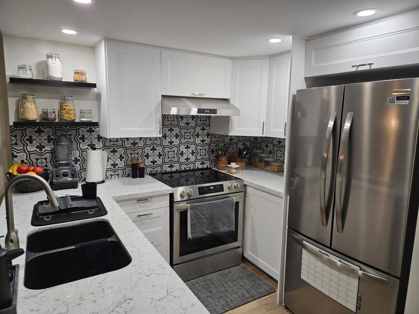 Etobicoke kitchen with black-and-white patterned tile backsplash and stainless fridge