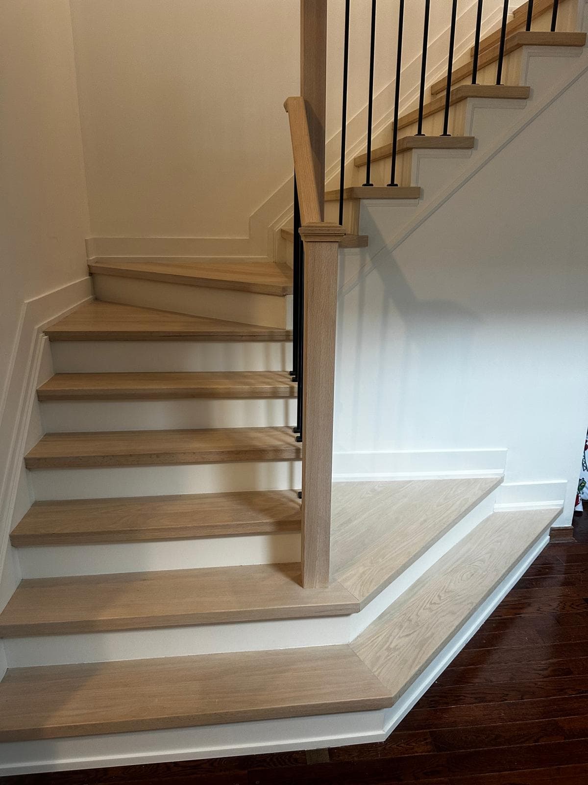 White oak stair install with painted risers and slim iron balusters