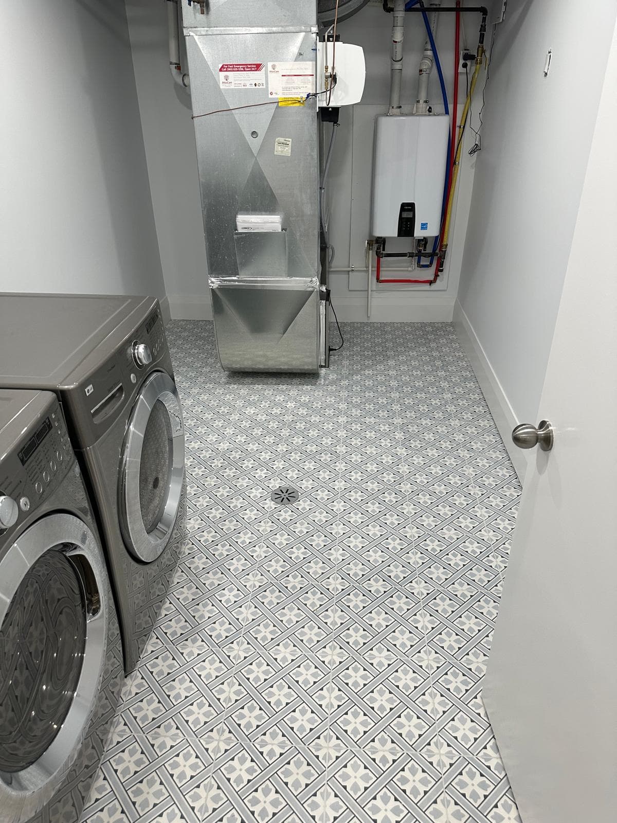 Patterned porcelain tile flooring in a basement laundry with appliances