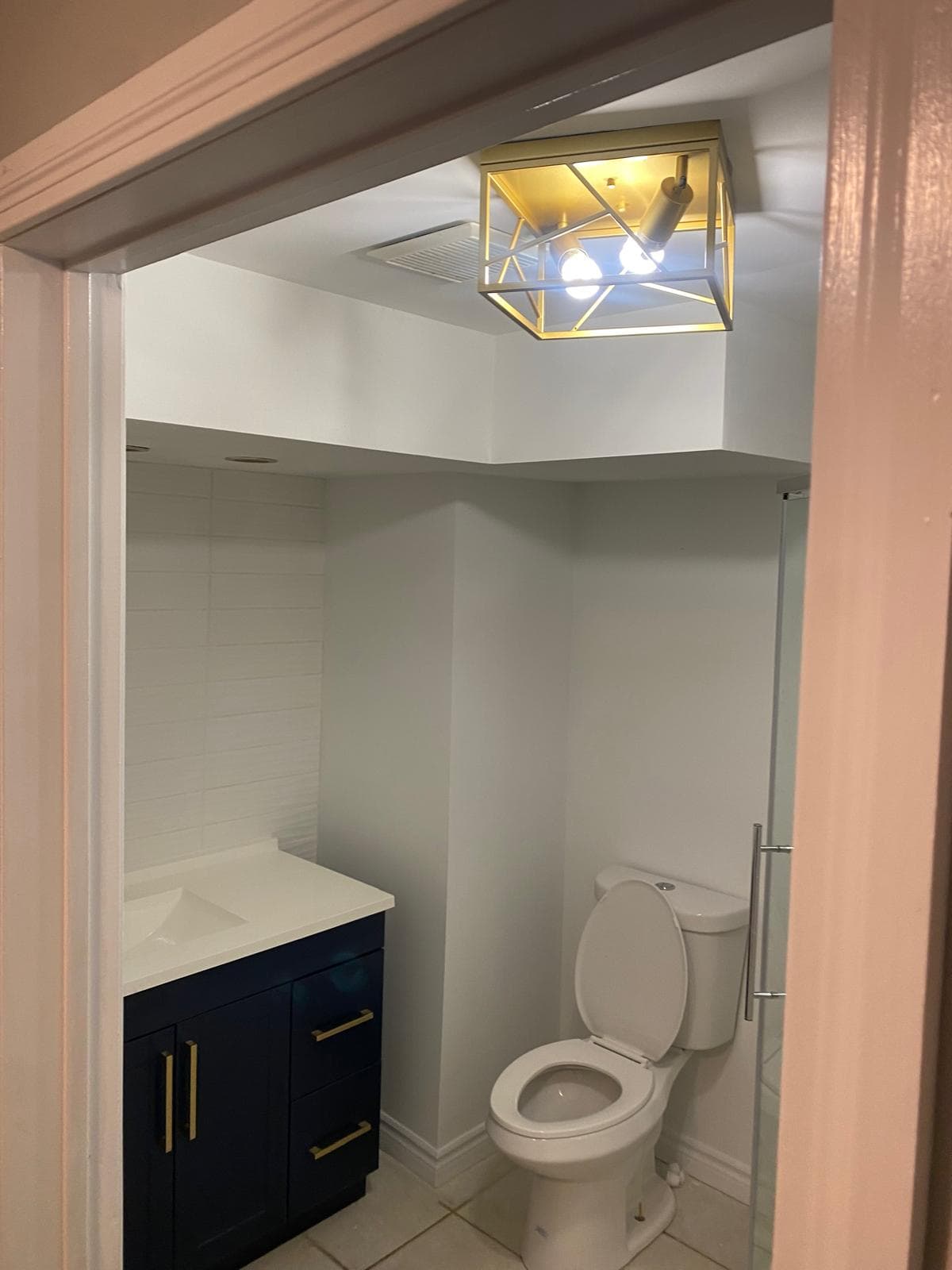 Small finished bathroom with navy shaker vanity and brass hardware