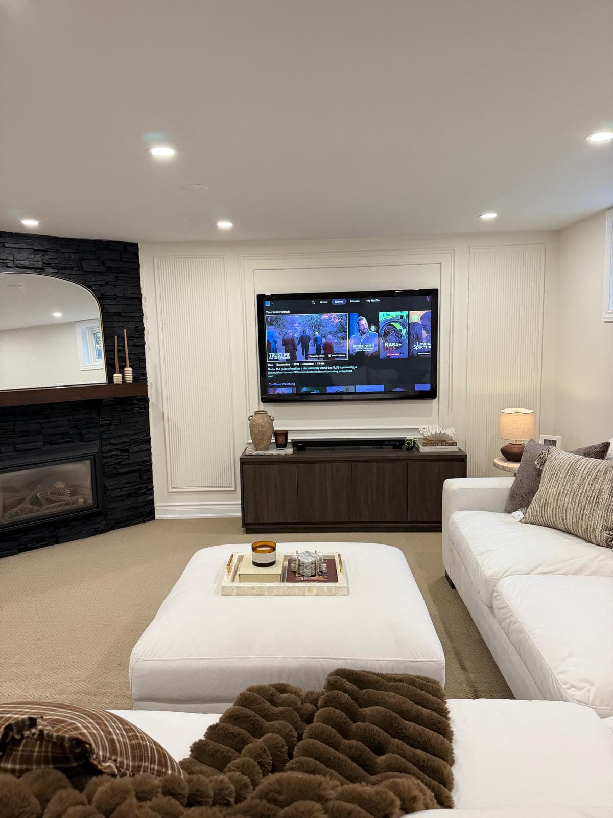 Mississauga rec room with black stone fireplace, mounted TV, and styled lounge