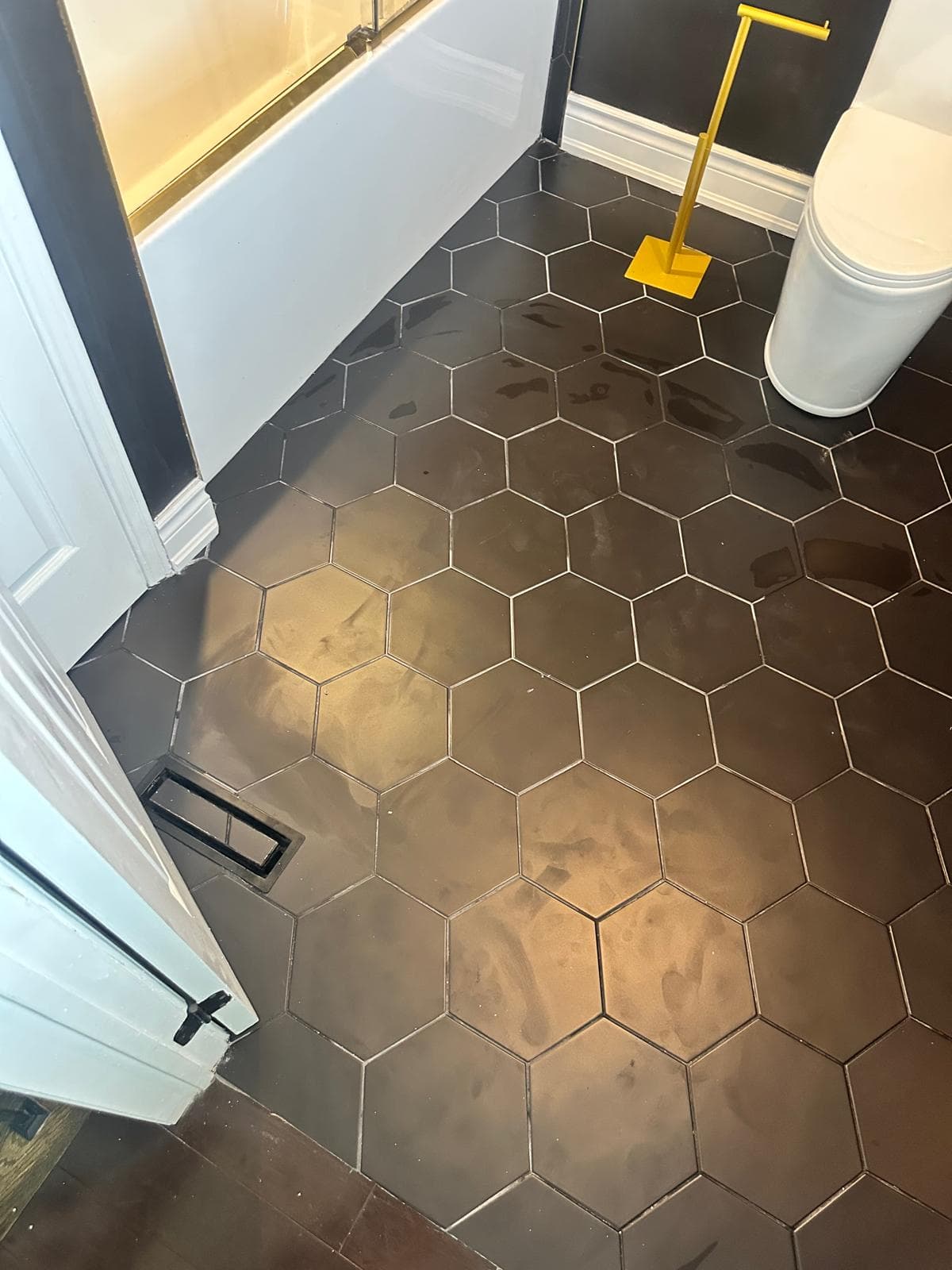 Black hexagon floor tile running to the doorway with a matte black floor vent