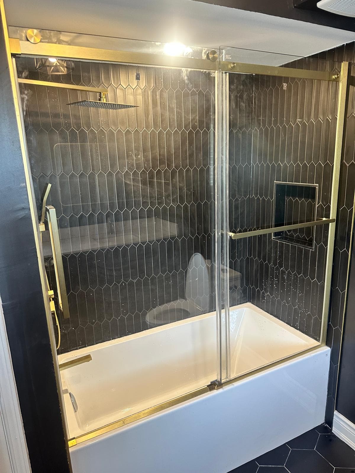 Top-down view of the black hexagon tile floor between the vanity and toilet
