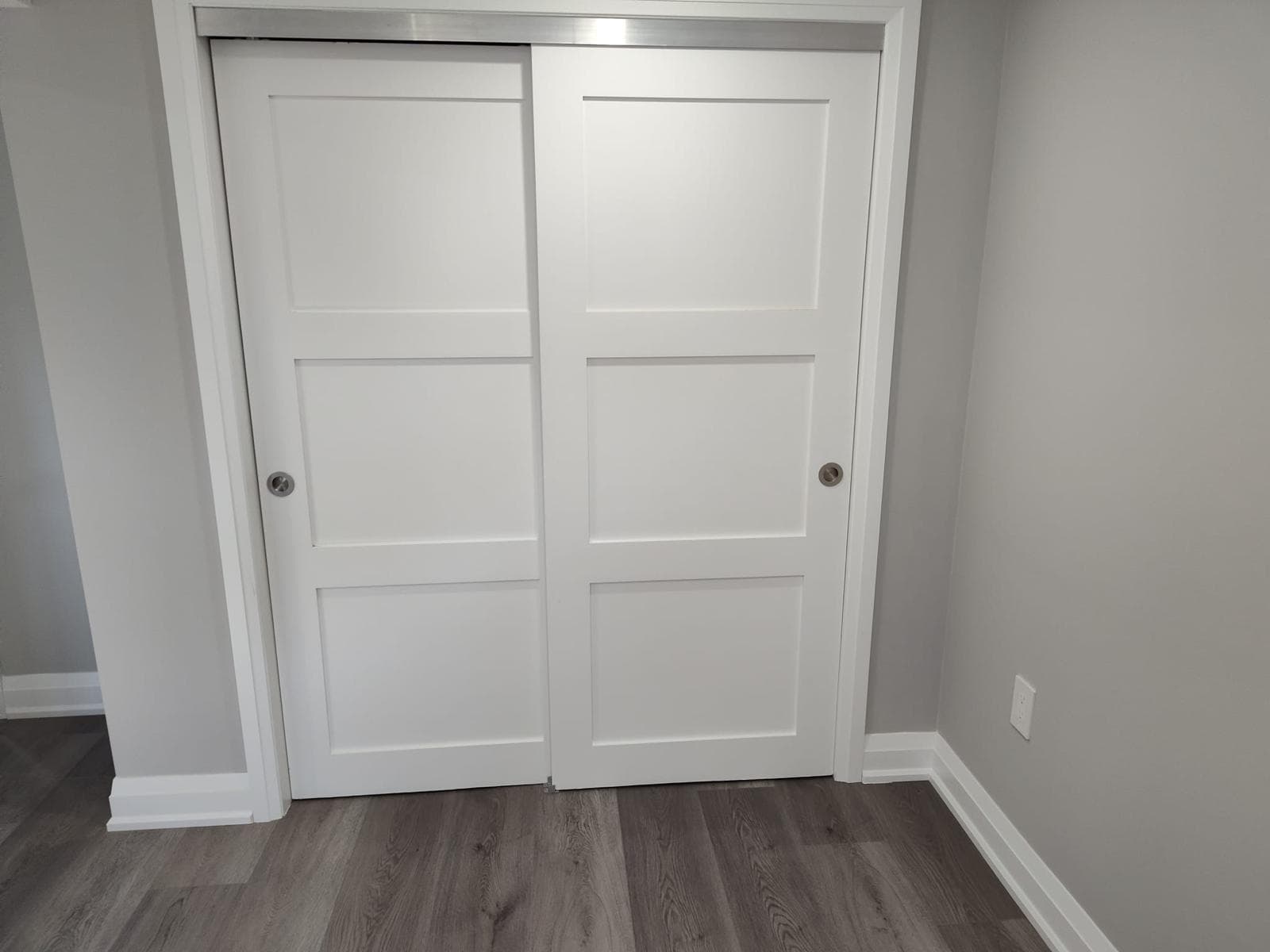 Finished room with grey wide-plank flooring and white sliding closet doors