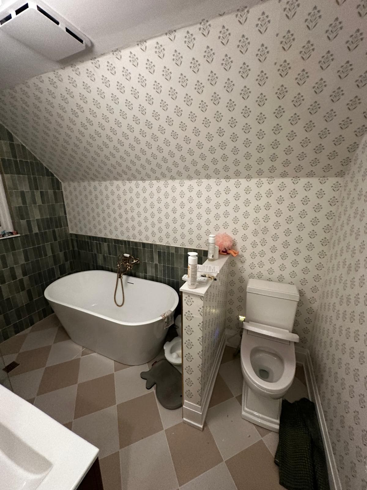 Same bathroom from the toilet side showing the wallpaper and freestanding tub