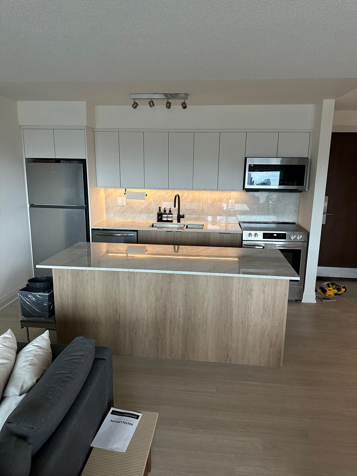 Modern condo kitchen with light wood island and white upper cabinets